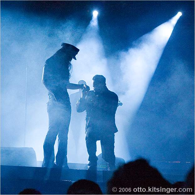 Live concert photo of Bono, fan, Adam Clayton (bg)