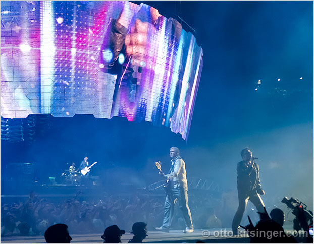 Live U2 concert photo of Larry Mullen Jr (bg), The Edge (bg), Adam Clayton, Bono